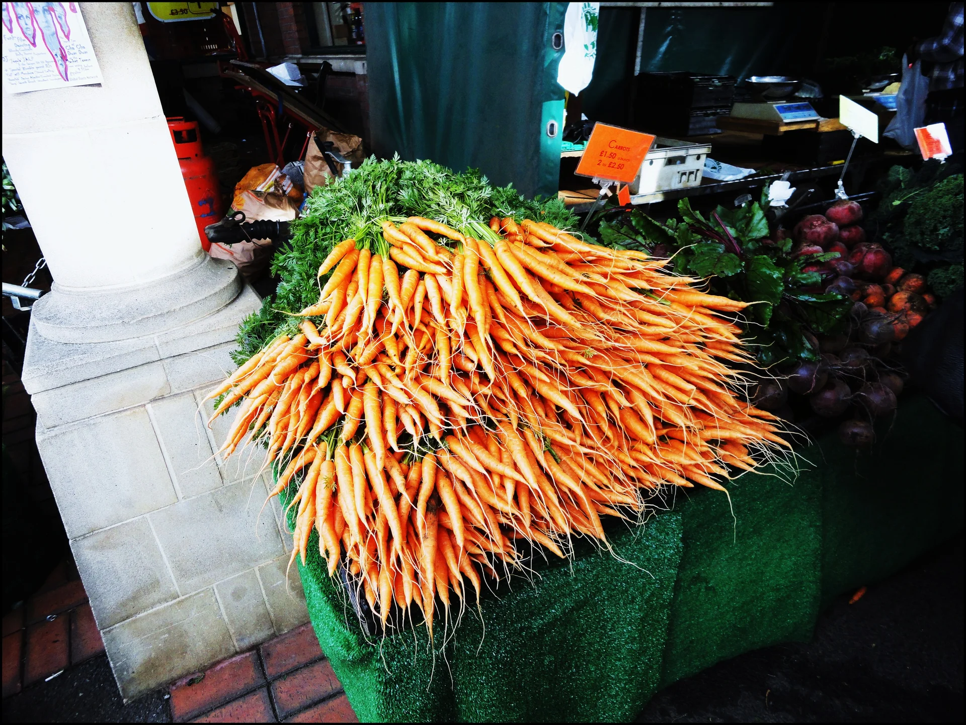 A large market bunch of ordinary orange carrots with their green leafy tops still on