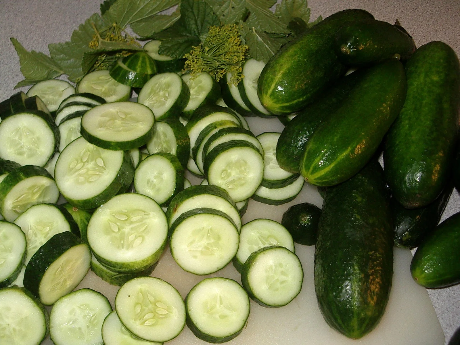 Whole and sliced fresh green cucumbers, showing the crisp pale flesh and soft seeds