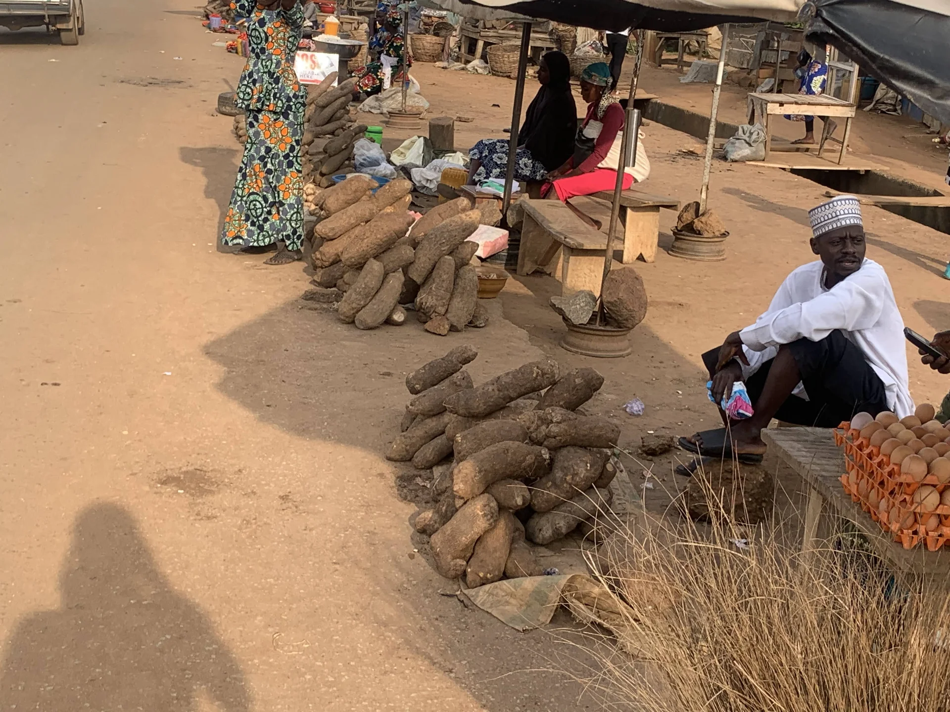 Piles of brown yam tubers for sale at a roadside market